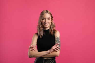 Photo of Beautiful woman with tattoos on arms against pink background