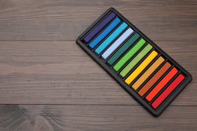 Colorful pastels in tray on wooden table, space for text. Drawing materials