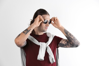 Young man with stylish tattoos on white background