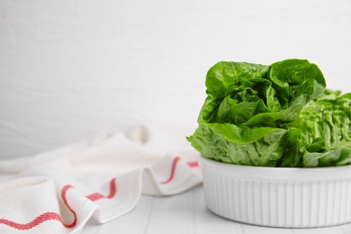 Photo of Bowl with fresh green romaine lettuces on white tiled table, space for text