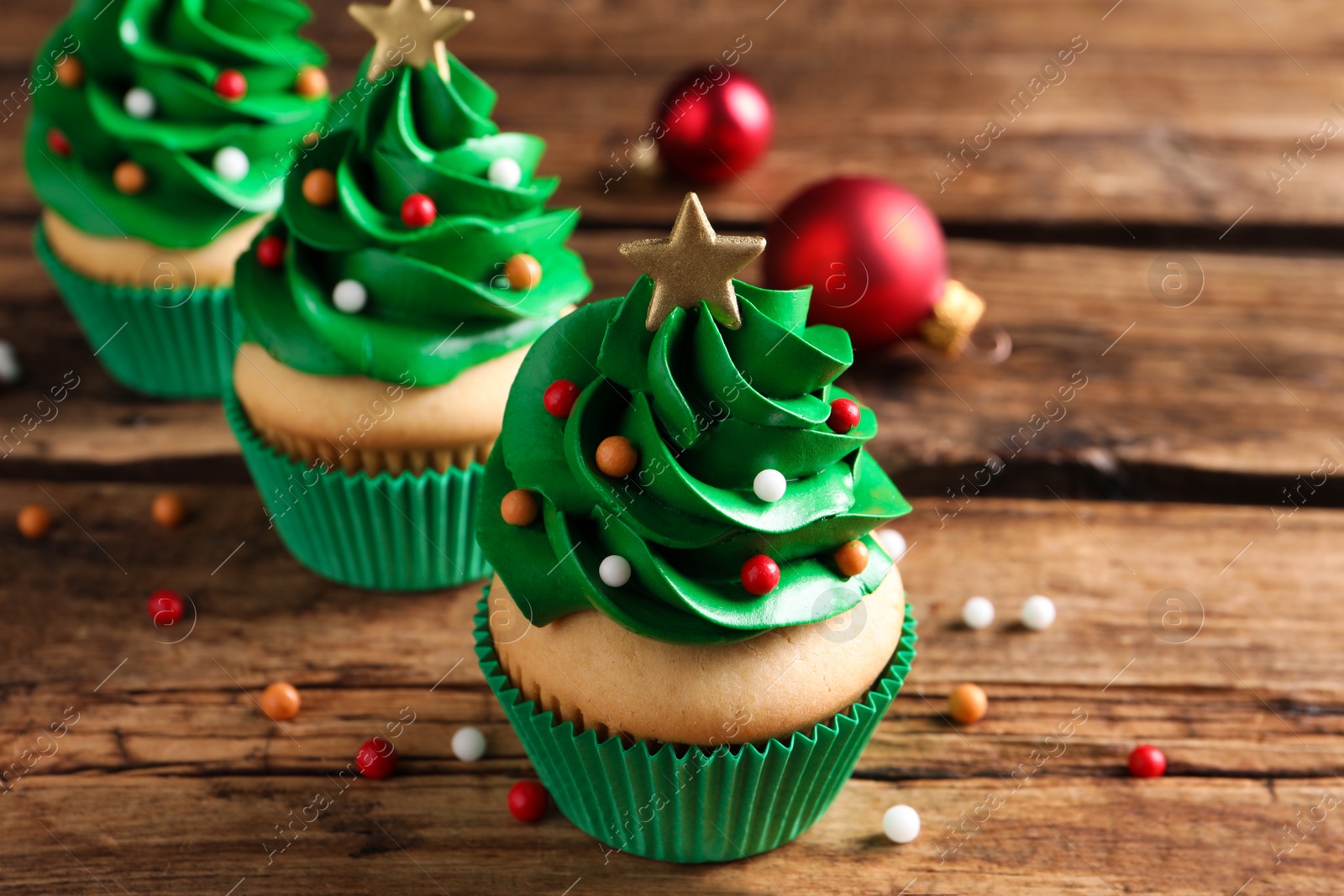 Photo of Christmas tree shaped cupcakes on wooden table