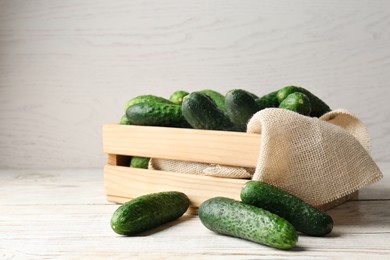 Photo of Crate full of fresh ripe cucumbers on white wooden table