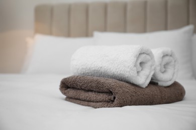 Photo of Soft clean towels on white bed indoors