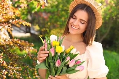 Photo of Beautiful young woman with bouquet of tulips in park on sunny day