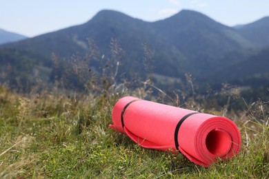 Photo of Rolled sleeping pad on grass in mountains, space for text