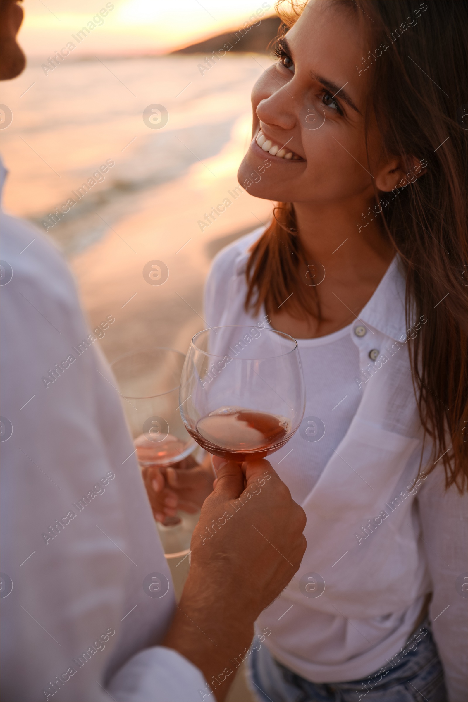 Photo of Couple with glasses of wine on beach at sunset