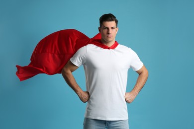 Photo of Man wearing superhero cape on light blue background