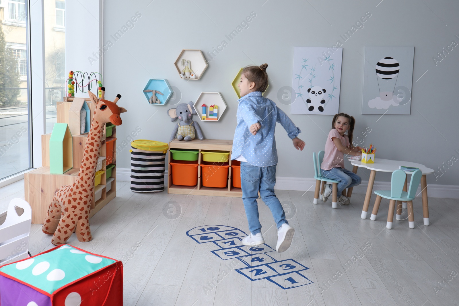 Photo of Cute little girls playing hopscotch at home