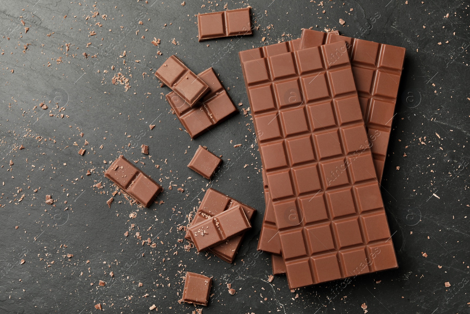 Photo of Pieces of tasty chocolate on grey table, flat lay