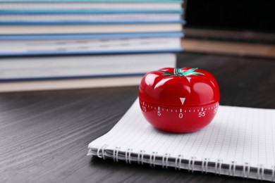 Kitchen timer in shape of tomato and notebook on wooden table, space for text