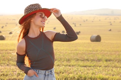 Photo of Beautiful happy hippie woman in hat in field, space for text