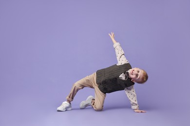 Photo of Happy little boy dancing on violet background. Space for text