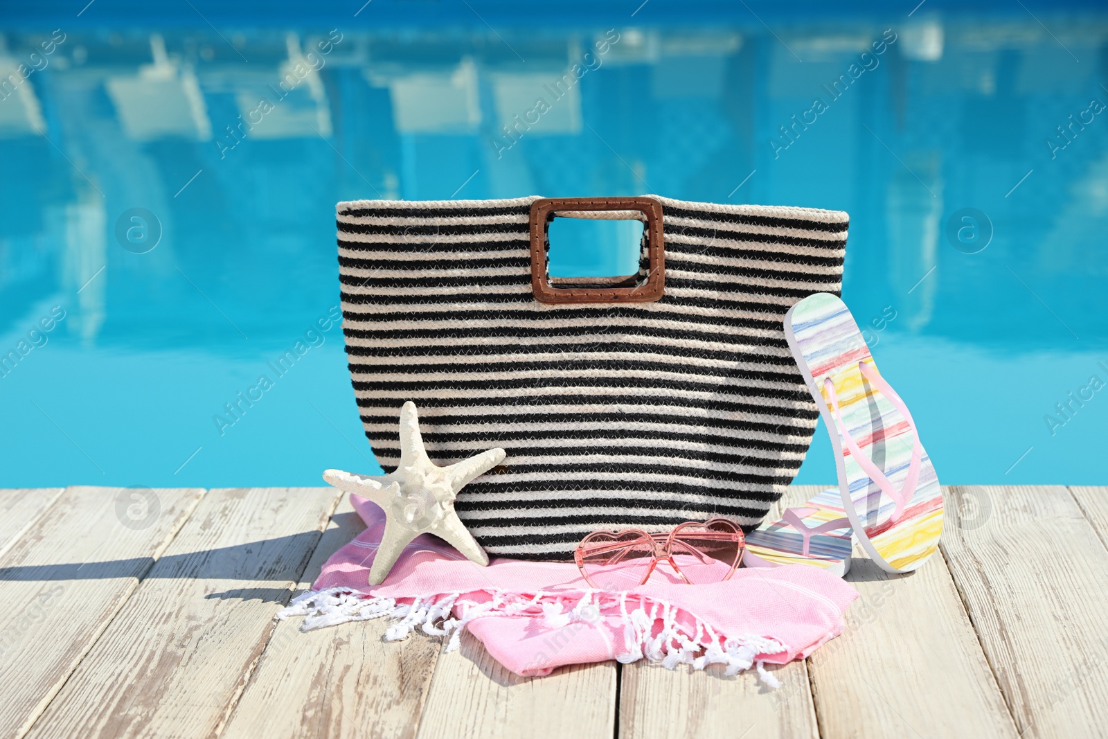 Photo of Beach accessories on wooden deck near outdoor swimming pool