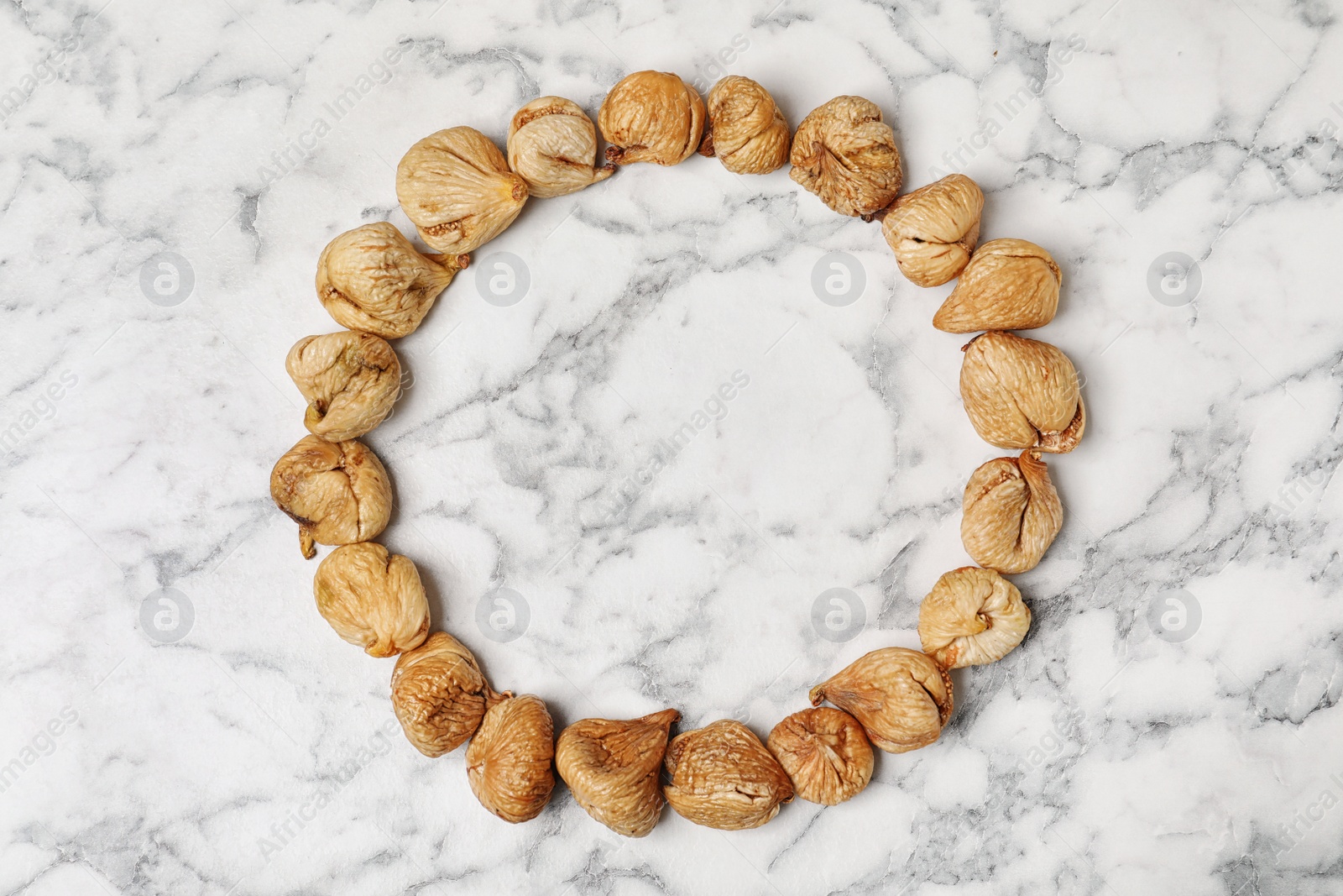 Photo of Frame made of figs on marble background, top view with space for text. Dried fruit as healthy food