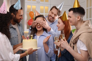 Photo of Happy friends with tasty cake celebrating birthday indoors