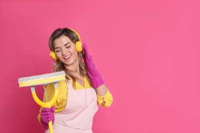 Photo of Beautiful young woman with headphones and mop singing on pink background. Space for text