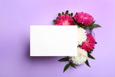 Photo of Flat lay composition with blank card and beautiful asters on lilac background, space for text. Autumn flowers