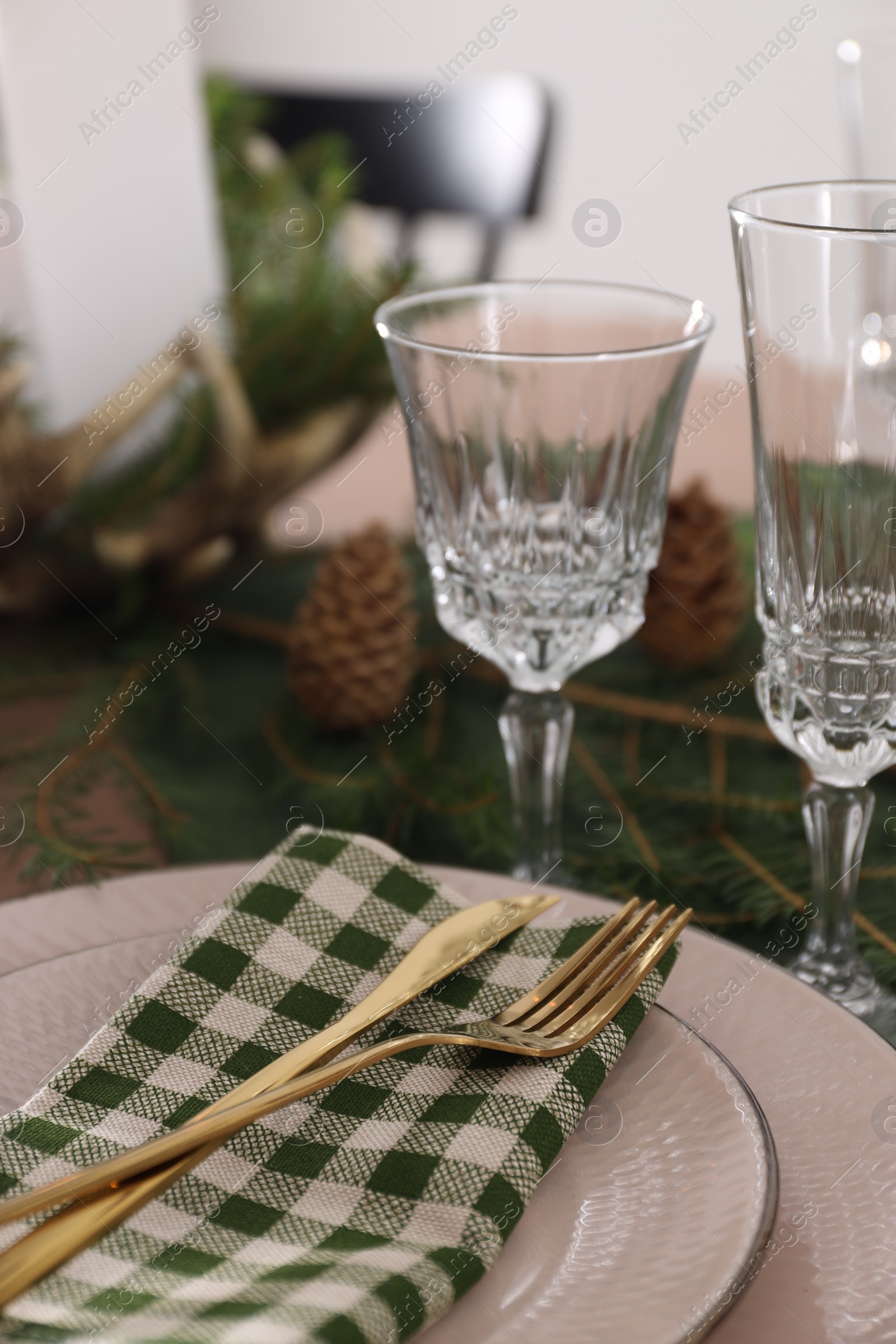 Photo of Christmas place setting with cutlery, glasses and festive decor on table, closeup