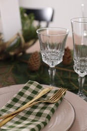 Christmas place setting with cutlery, glasses and festive decor on table, closeup