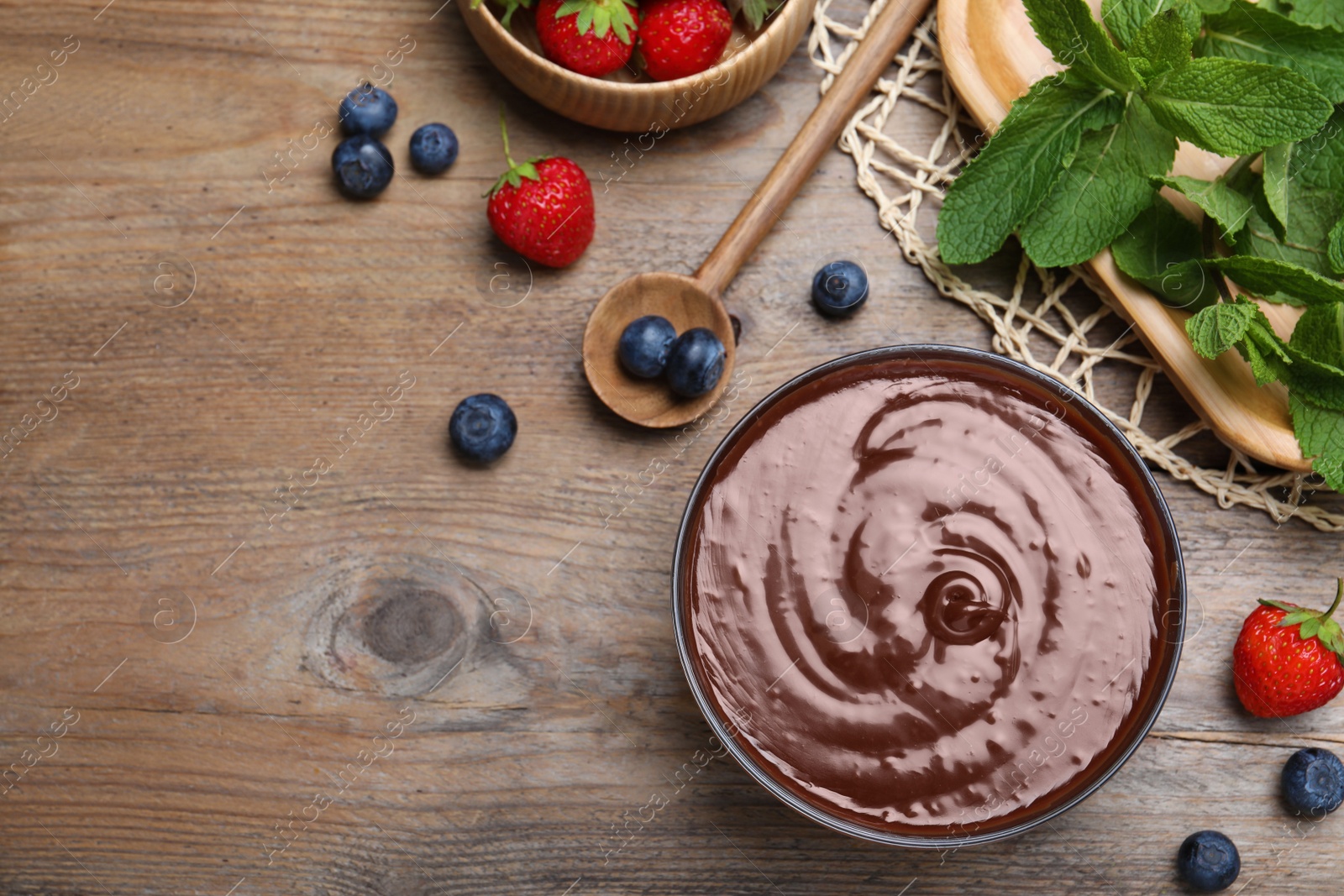 Photo of Delicious chocolate cream with berries and mint on wooden table, flat lay. Space for text