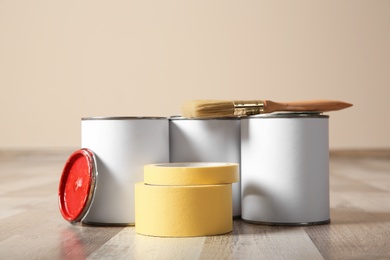 Cans of paint and decorator tools on wooden floor indoors