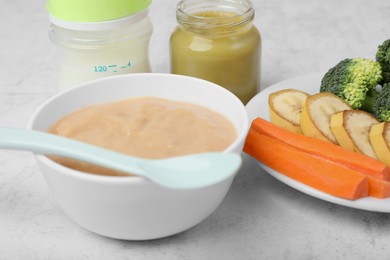Photo of Bowl with healthy baby food and ingredients on white table, closeup