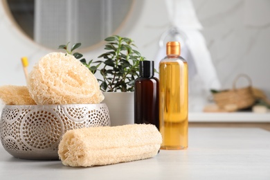 Natural loofah sponges and personal hygiene products on table in bathroom