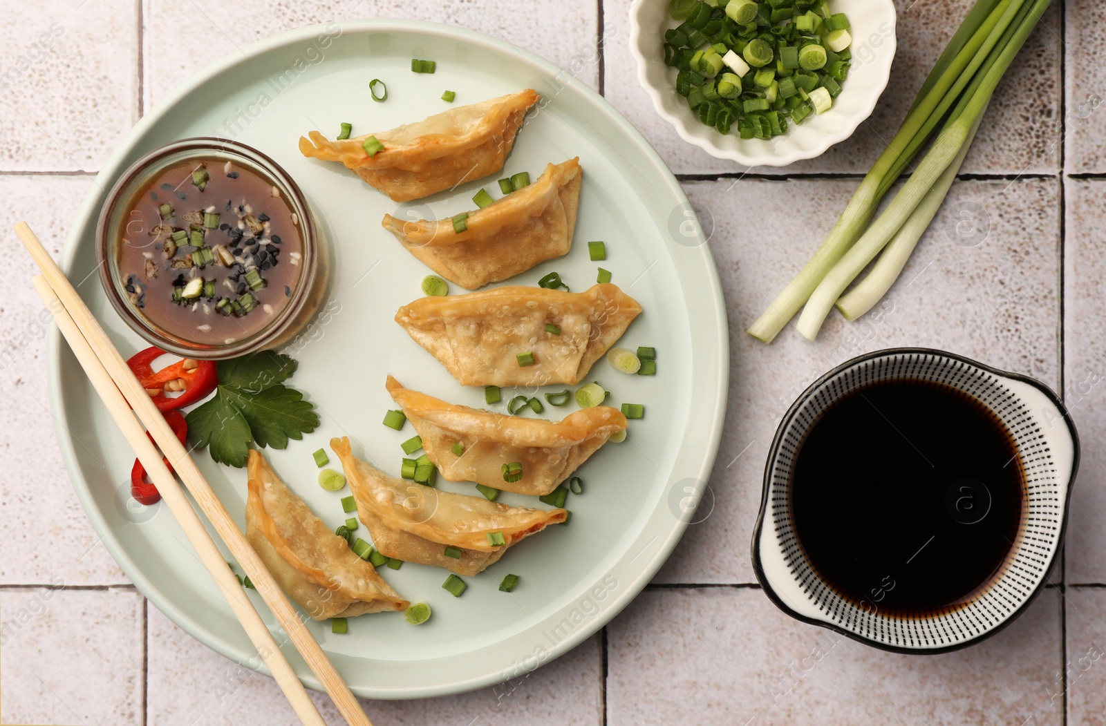 Photo of Delicious gyoza (asian dumplings) served on light tiled table, flat lay