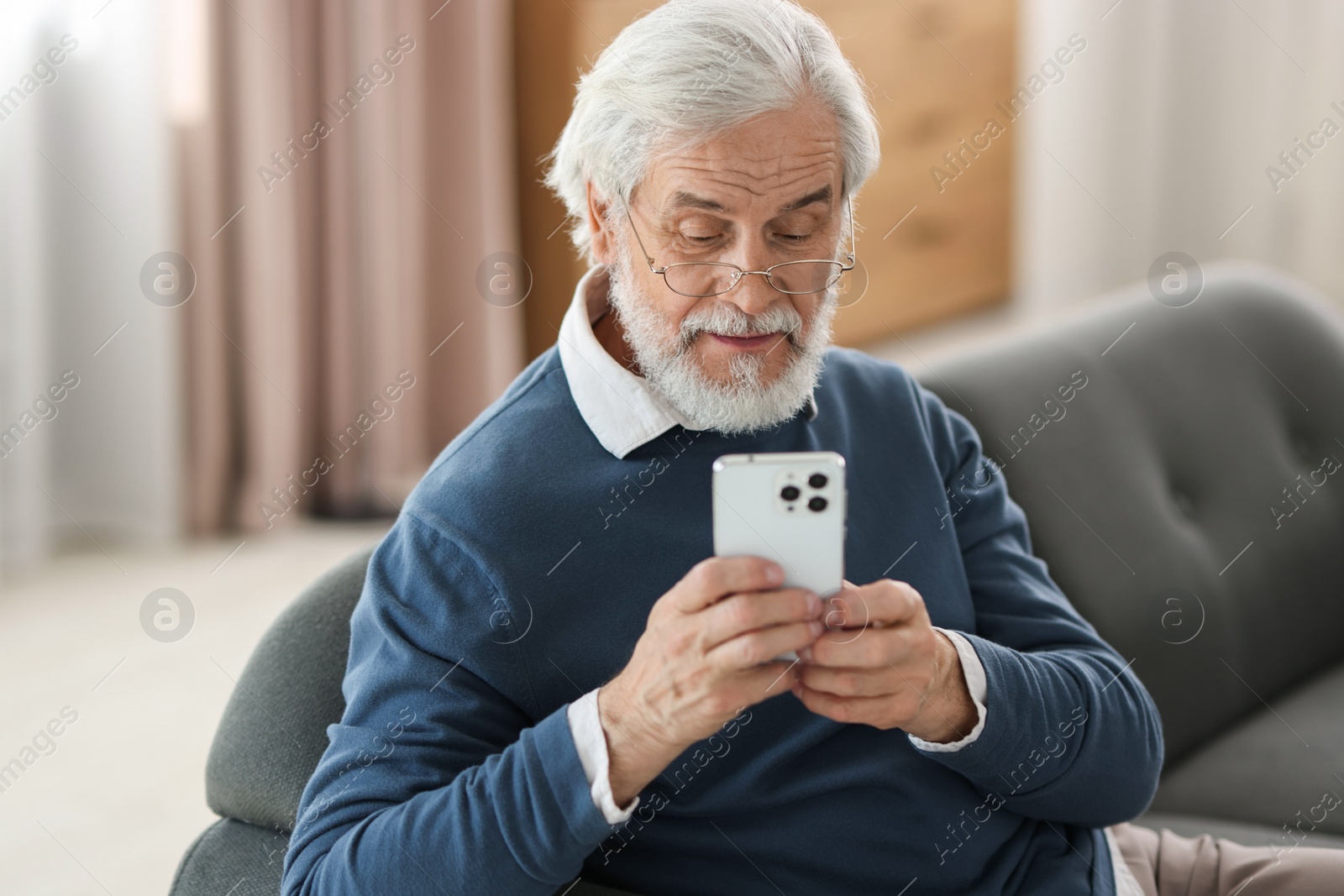 Photo of Portrait of happy grandpa with glasses using smartphone indoors