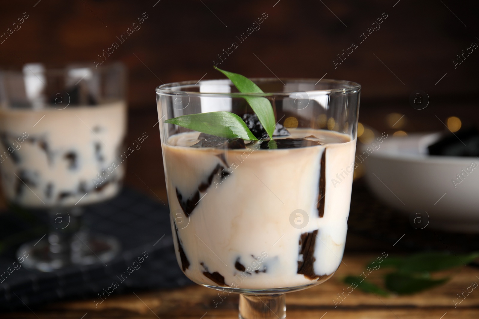 Photo of Glass of milk with grass jelly and green leaves, closeup