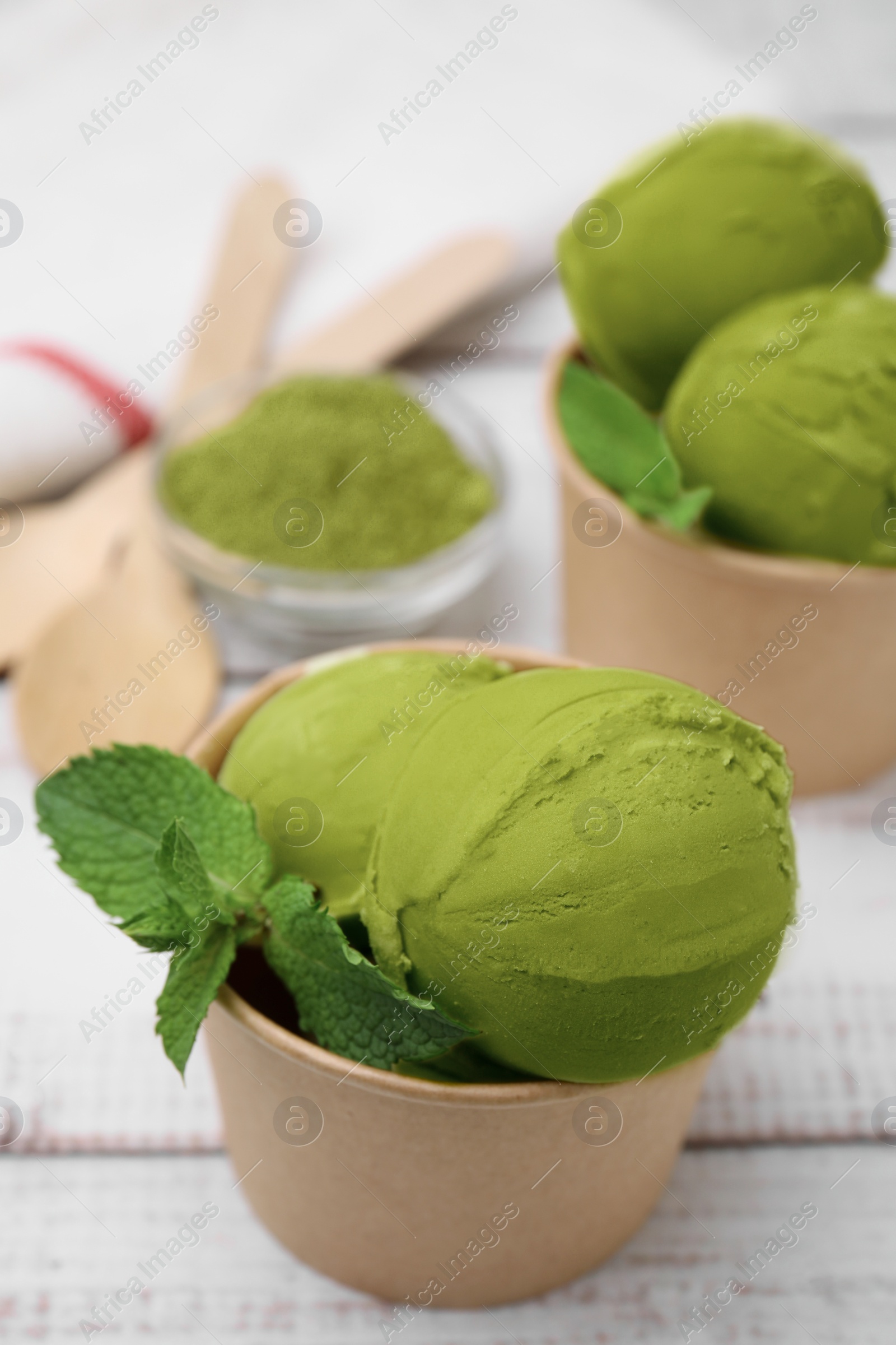 Photo of Paper cups with tasty matcha ice cream on white wooden table