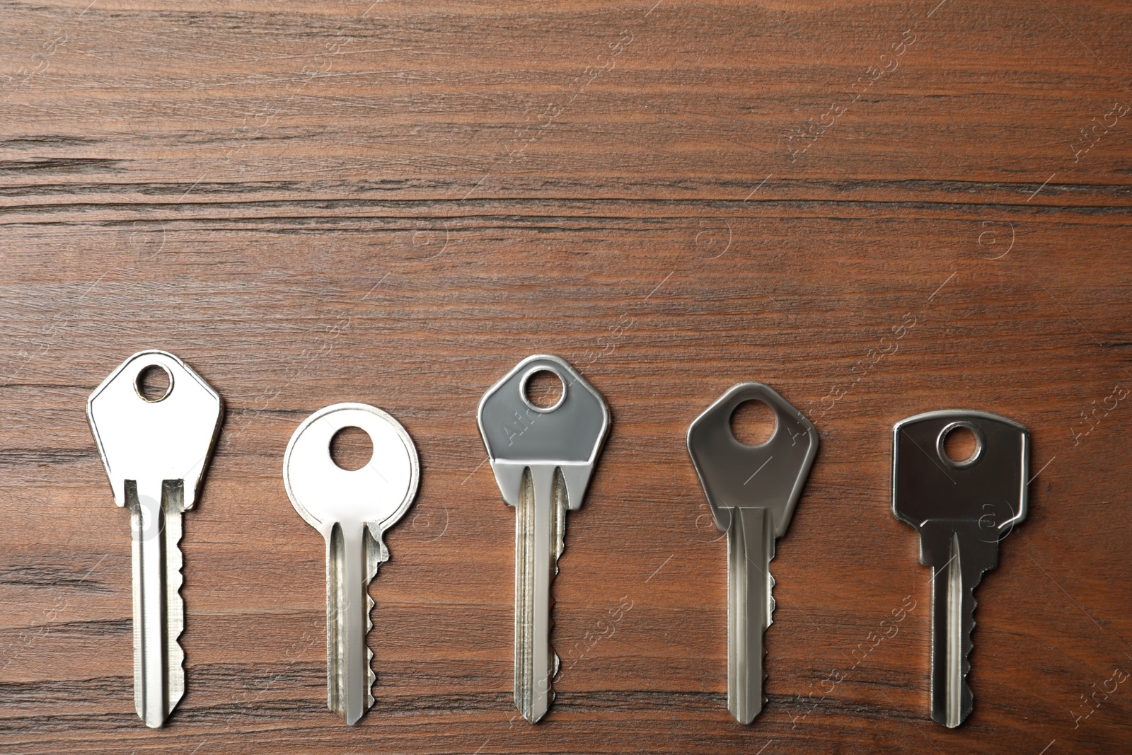 Photo of Steel keys on wooden background, flat lay with space for text. Safety concept