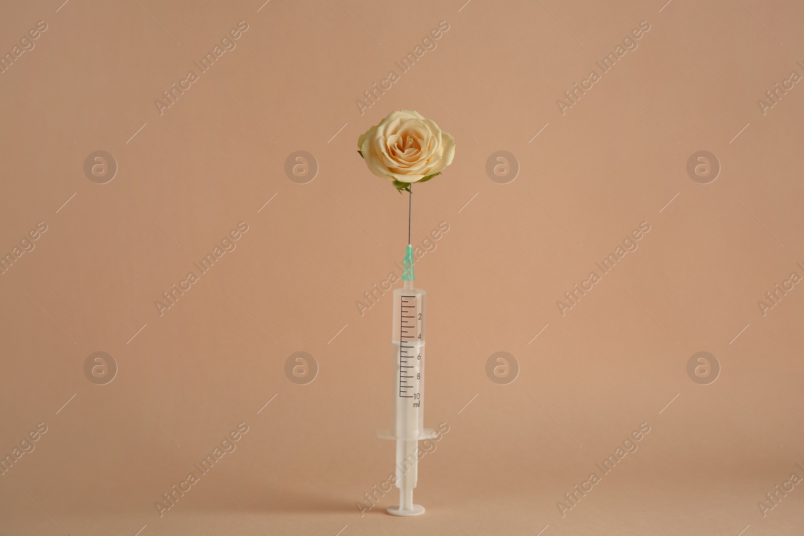 Photo of Medical syringe and rose flower on beige background