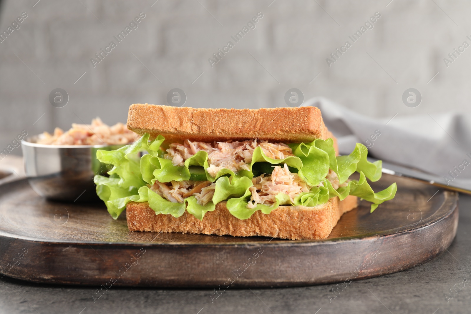 Photo of Delicious sandwich with tuna, lettuce leaves and cucumber on light grey table