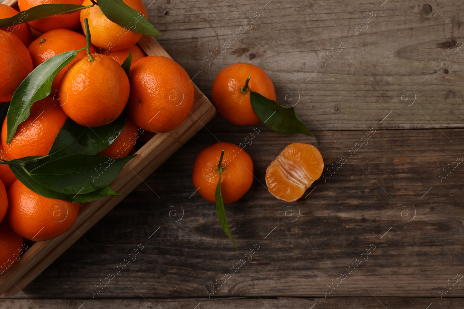 Photo of Delicious tangerines with leaves on wooden table, flat lay. Space for text