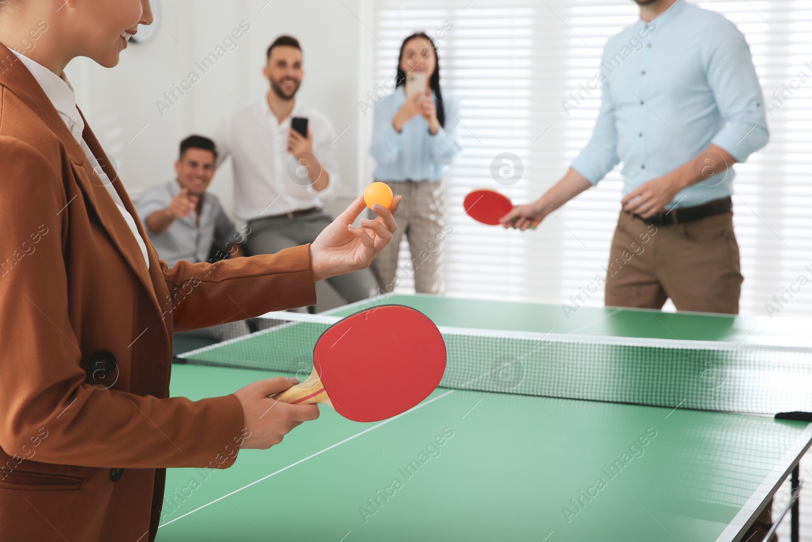 Photo of Business people playing ping pong in office, focus on tennis racket. Space for text