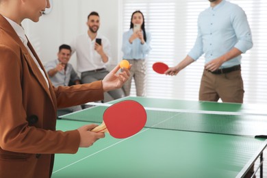 Photo of Business people playing ping pong in office, focus on tennis racket. Space for text