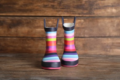 Photo of Pair of striped rubber boots on wooden surface