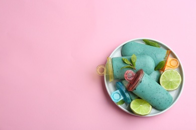 Photo of Plate with delicious spirulina popsicles and lime on color background, top view. Space for text