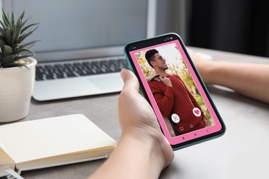 Image of Woman visiting dating site via smartphone at table, closeup