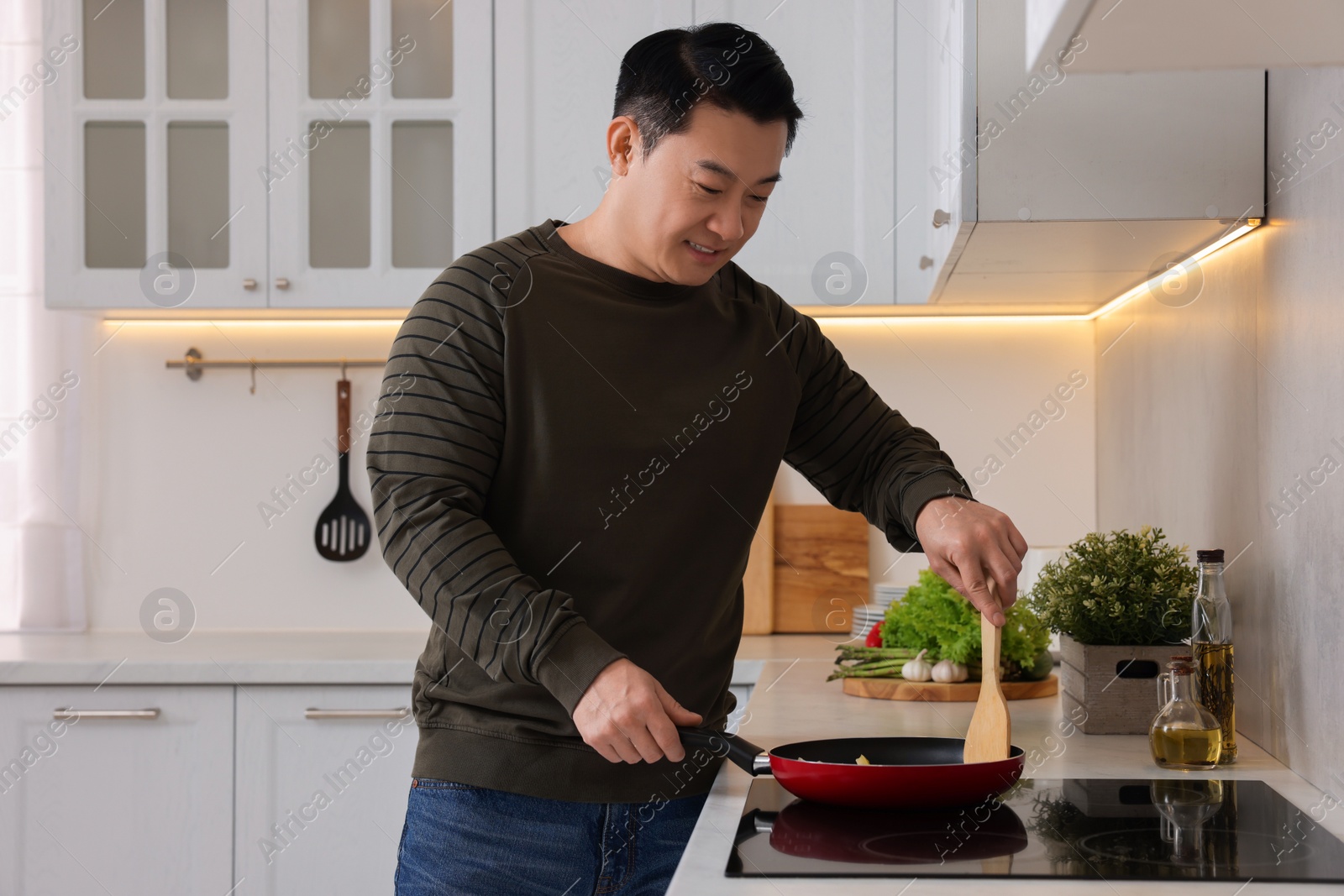 Photo of Man with frying pan cooking in kitchen