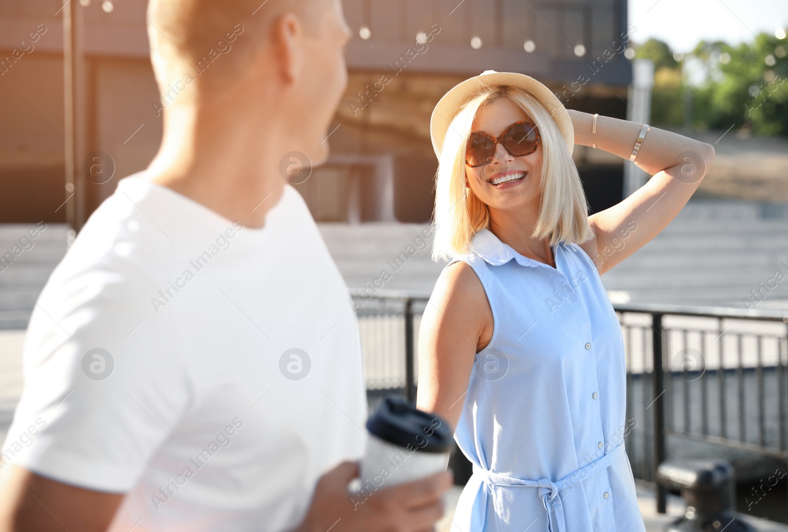 Photo of Happy couple with drink walking along city street on summer day