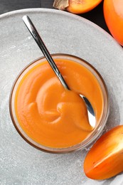 Photo of Delicious persimmon jam in glass bowl served on table, top view