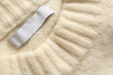 Blank clothing label on white cashmere sweater, top view