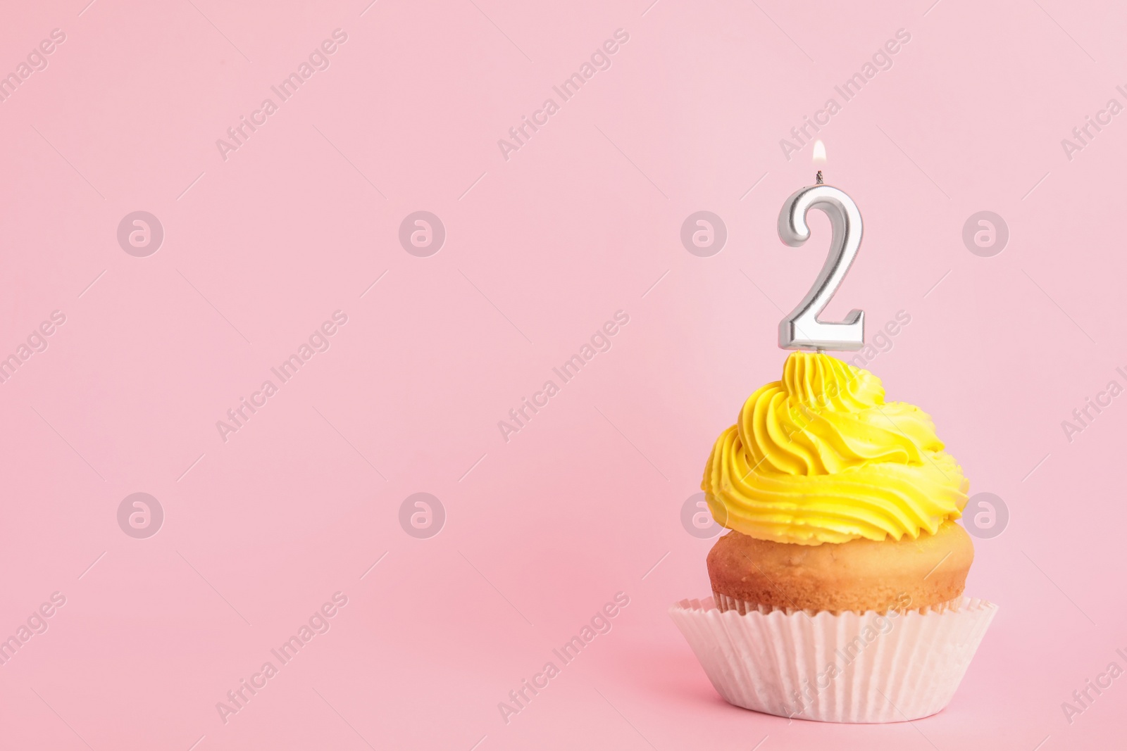 Photo of Birthday cupcake with number two candle on pink background, space for text