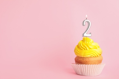 Photo of Birthday cupcake with number two candle on pink background, space for text
