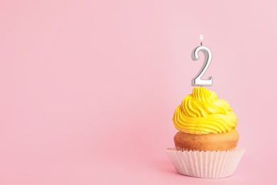 Birthday cupcake with number two candle on pink background, space for text