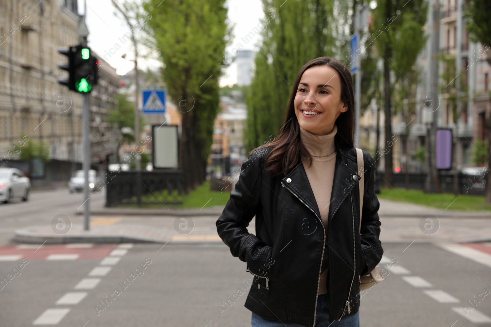 Photo of Young woman crossing street at traffic lights