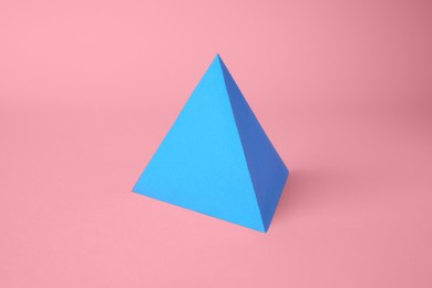 Photo of Origami art. Paper pyramid on pink background