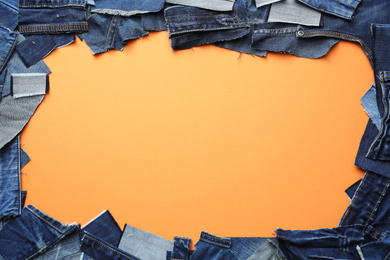 Photo of Frame made of cut jeans on orange background, flat lay. Space for text